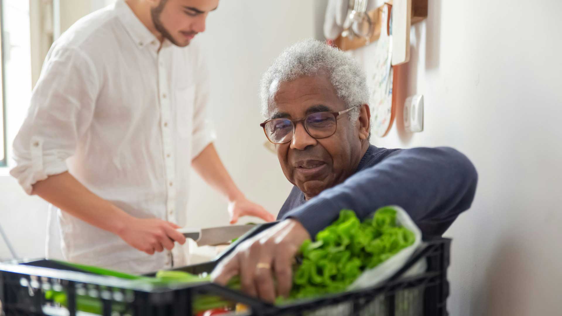 Bastrop county cares change agents. Older man and young man unloading vegetables from crate