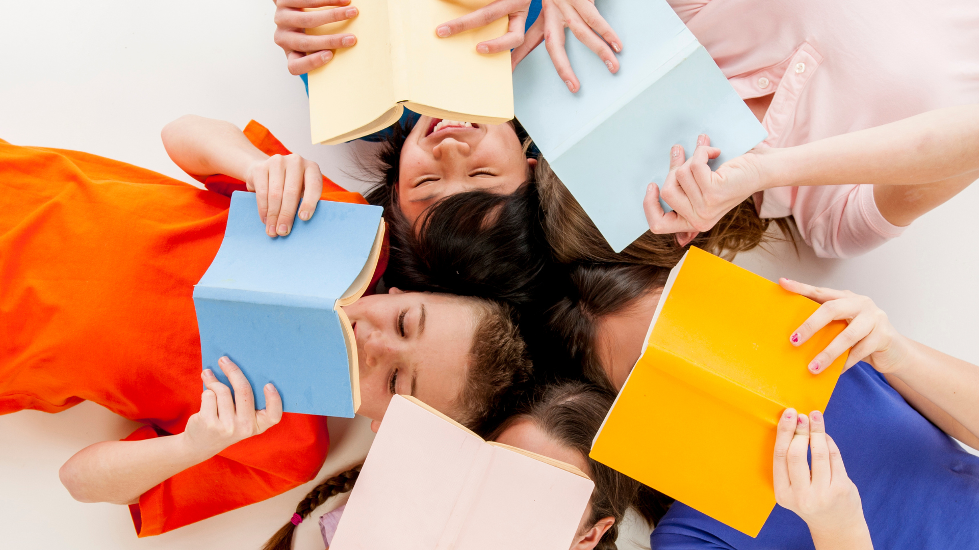 Children laying down in a circle reading colorful books
