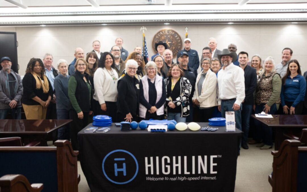 Community partners pose together in a meeting room behind a table displaying Highline internet materials.