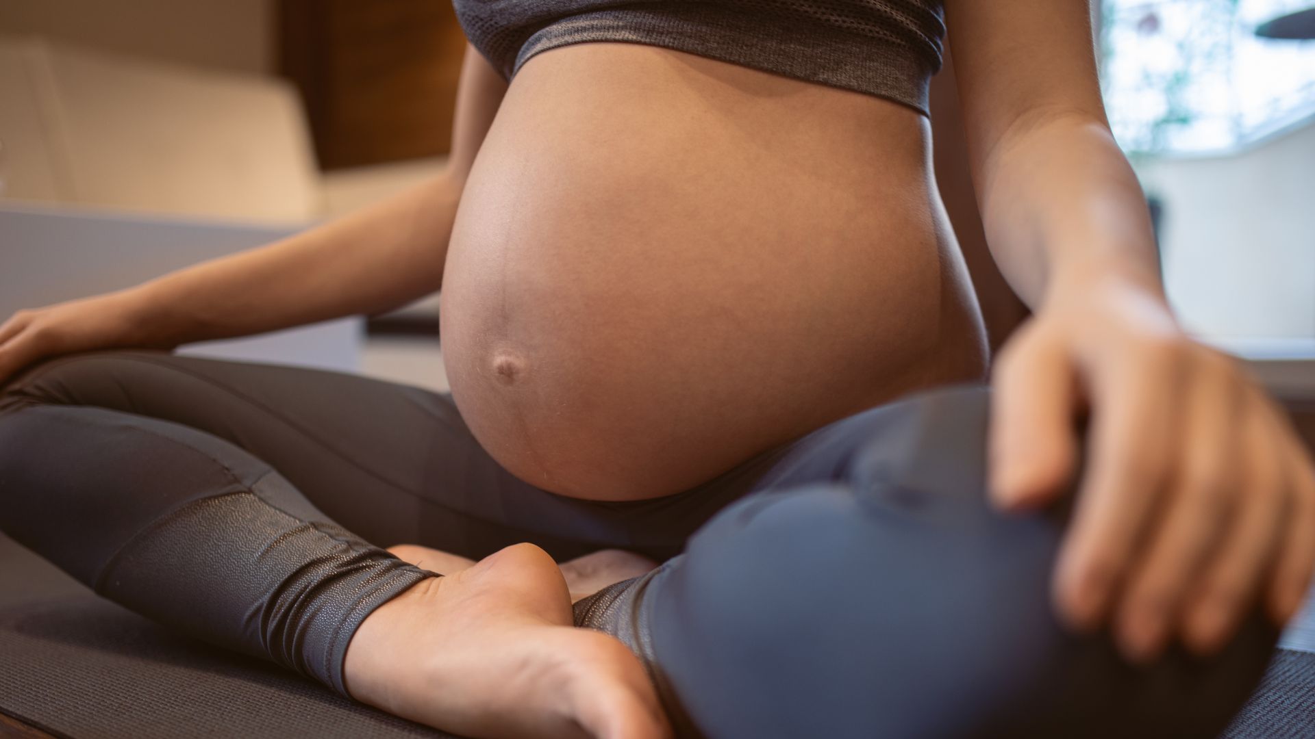 Pregnant person sitting cross-legged and practicing prenatal yoga or meditation.