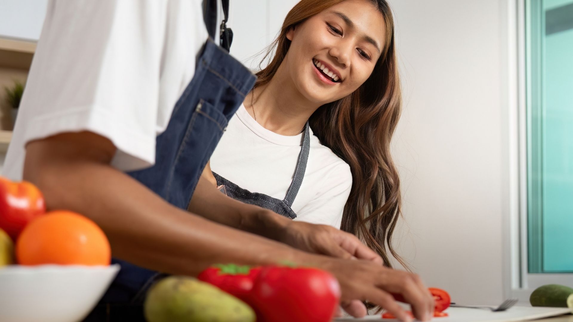 Teen student smiles while learning to prepare healthy food with an instructor during a hands-on wellness activity focused on healthy habits and life skills.