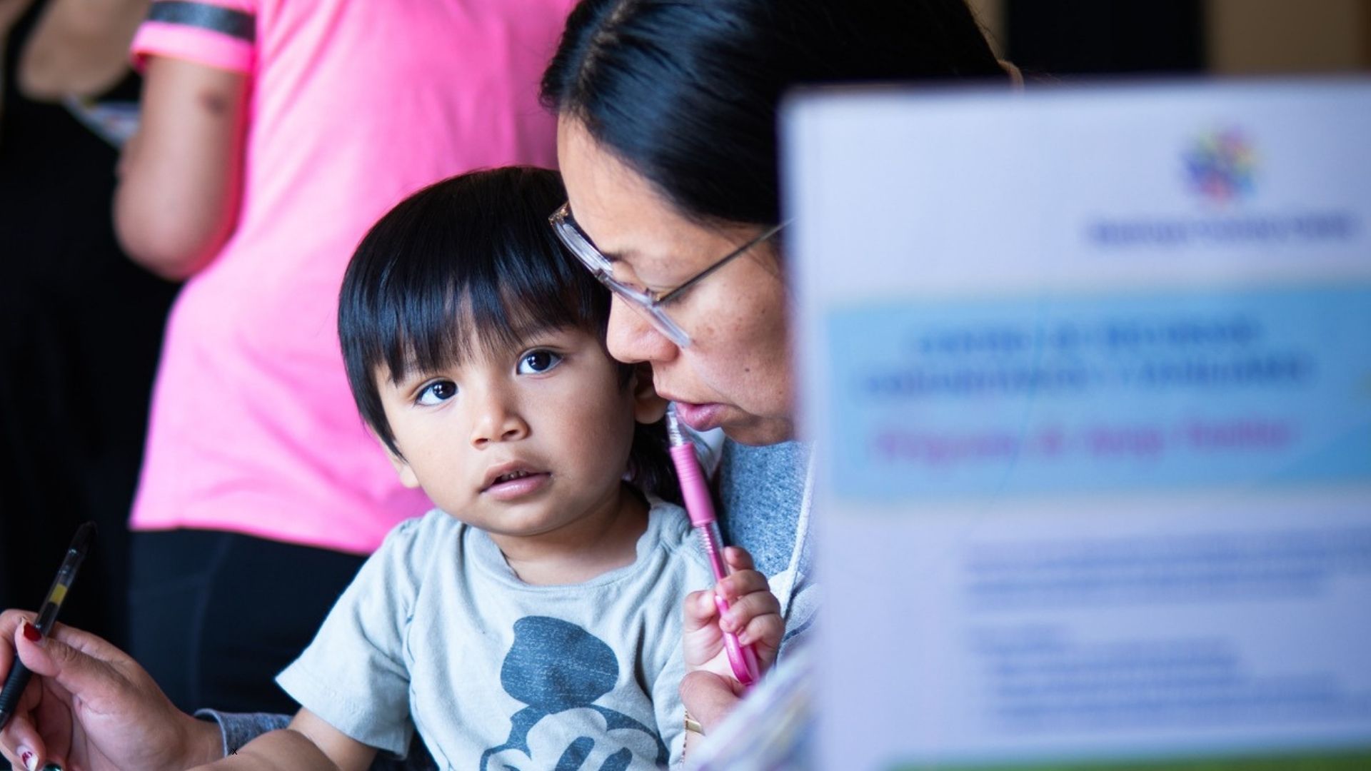 Toddler sits with a caregiver while participating in an early learning activity during a Bastrop County Cares toddler program.