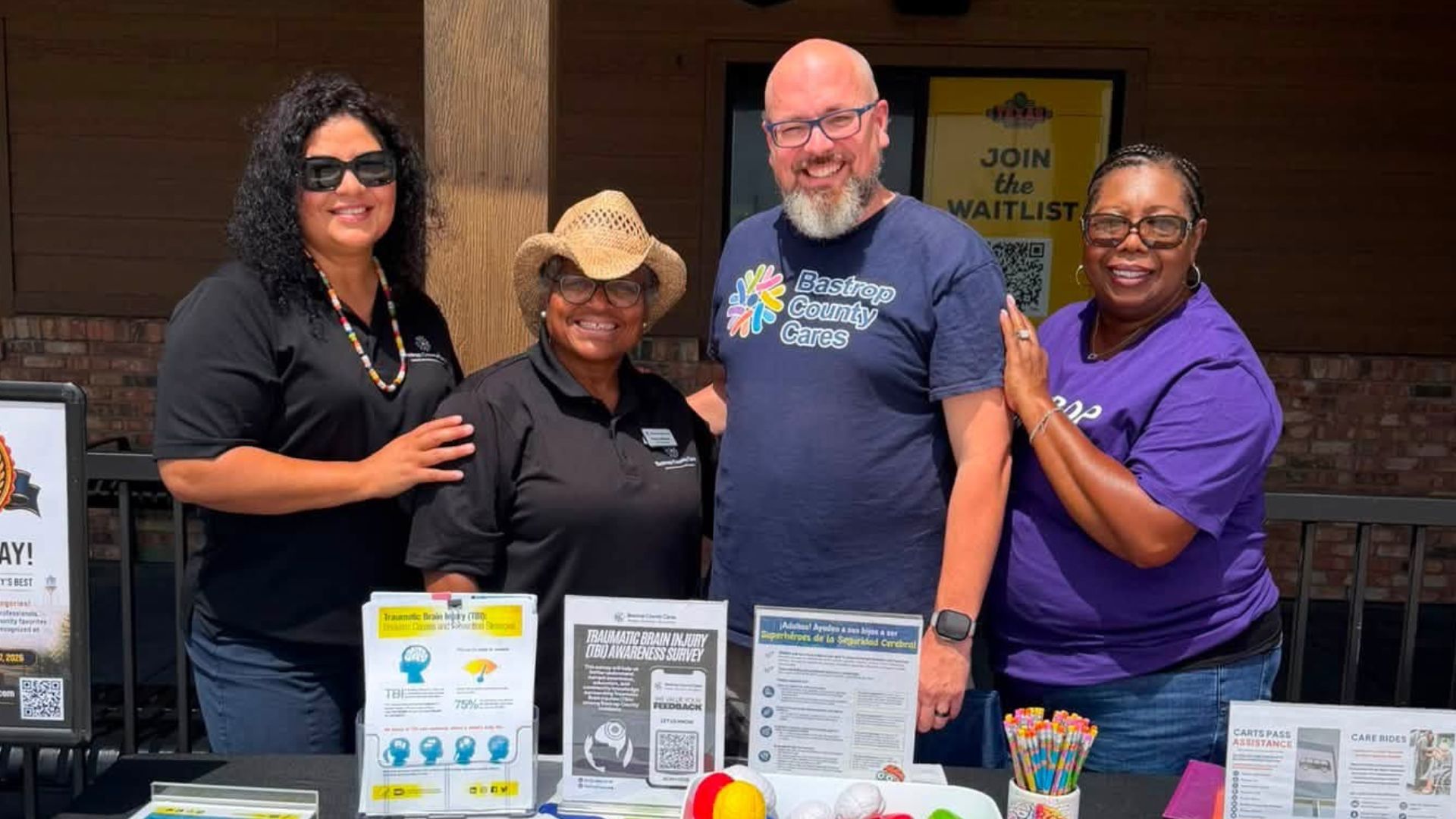 Bastrop County Cares staff and community partners at an outreach table during the Texas Roadhouse Bastrop soft opening event.