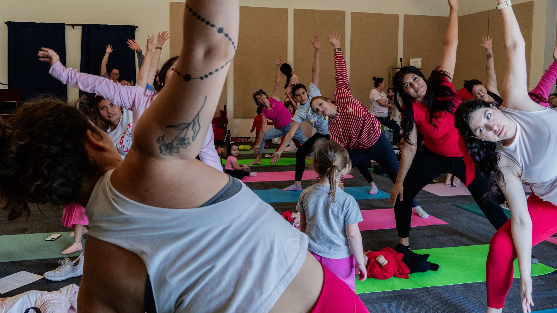 Moms and young children participate together in a family-friendly movement and wellness class hosted by Bastrop County Cares.