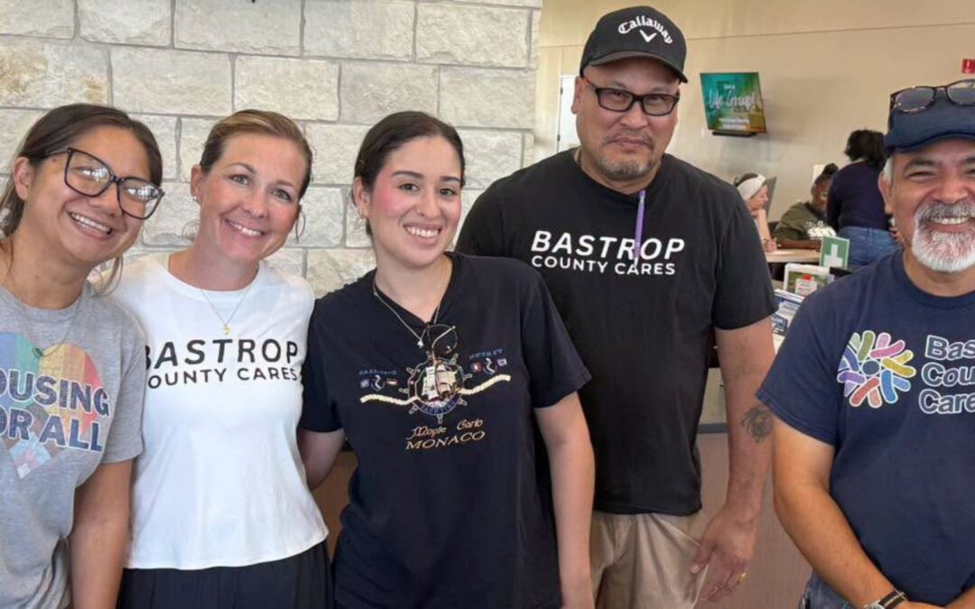 Five Bastrop County Cares team members smiling together at a community event.
